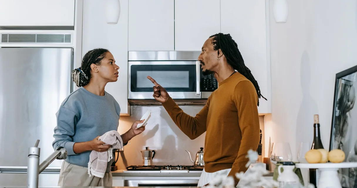Homem apontando o dedo para a mulher durante discussão na cozinha, manipulação de um dependente químico