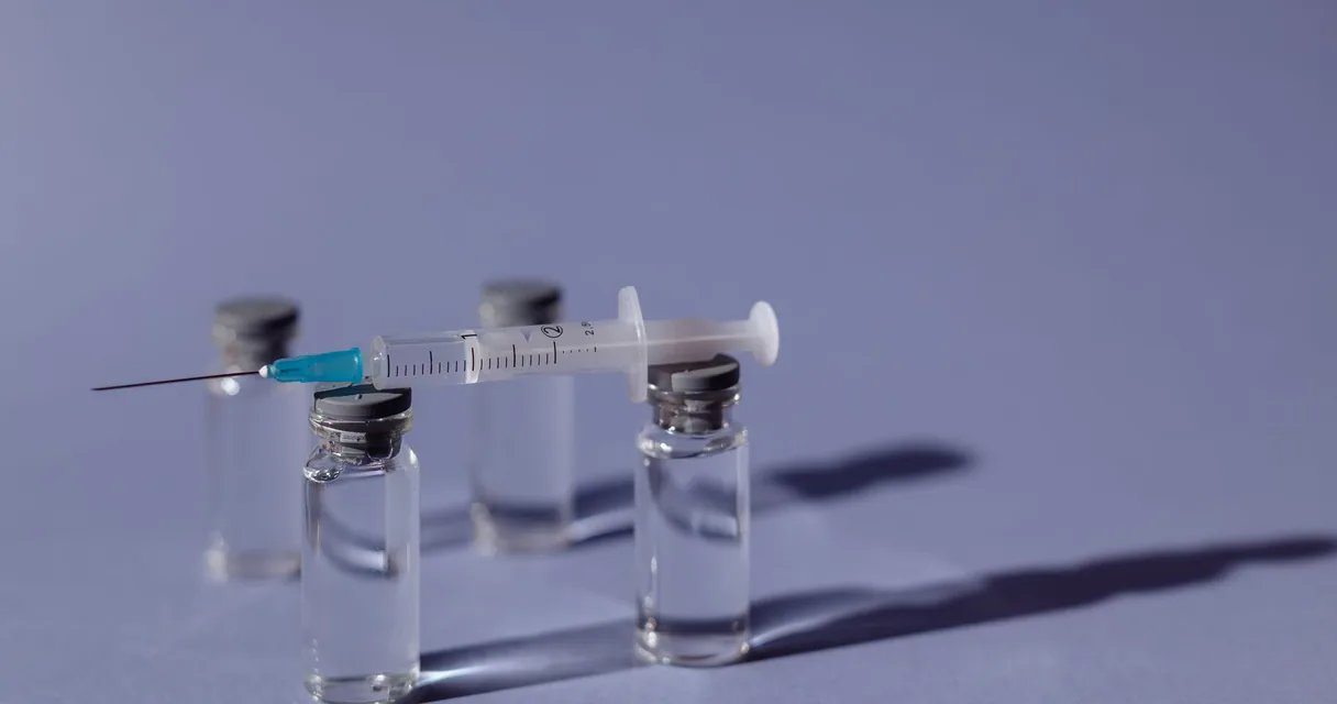 Ampolas de vacina e seringa sobre fundo azul, pesquisas de vacina contra a dependência de cocaína e crack